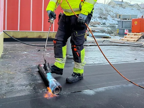 Mann i arbeidsklær utfører membrantekking